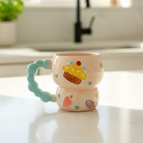 Keeyos PH pastel pink ceramic mug with beaded blue handle, featuring a cupcake illustration and scattered hearts.