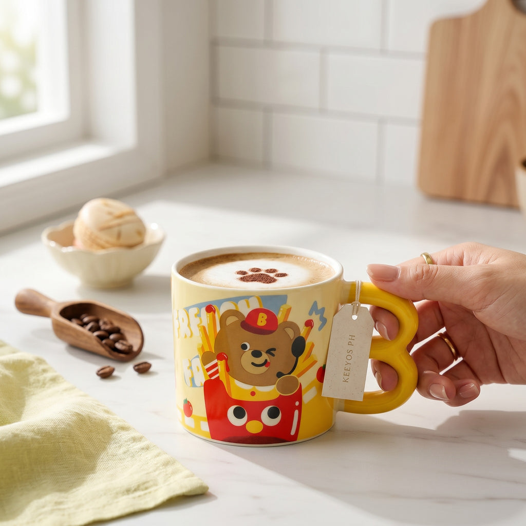 Keeyos PH yellow mug with a cartoon bear in a french fries box design. Features a red hat with a B and a playful wink.
